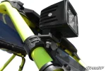 Cage light mounting bracket clamped to a green cage tube holding a black LED cube light