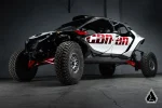 Black, white and red four seat Can-Am Maverick R MAX in a warehouse with rock sliders fitted below the doors