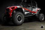 Red and silver four seat Polaris RZR XP 4 1000 in a dark studio with rock sliders fitted below the doors