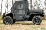 Can-Am Defender with full cab enclosure doors installed, parked on grass in bare winter woods