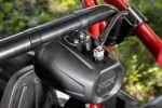 UTV speaker pod clamped to a roll cage tube on a machine with a red frame, sealed wiring connector attached