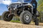 Polaris Ranger with a winch fitted up front climbing a dirt berm on a wooded trail