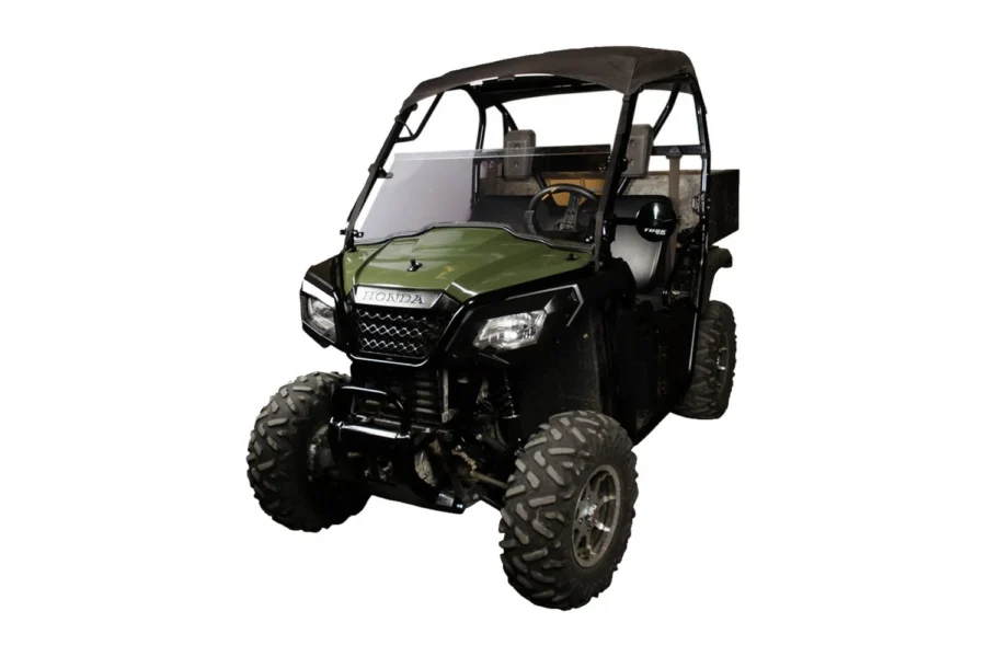 Tusk hinged UTV windshield mounted on a green Honda Pioneer, front three-quarter view
