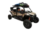 Tan Polaris RZR XP 4 turbo with the Tusk roof rack loaded with gear bags, front three-quarter view