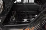 Tusk black seat cargo rack installed behind the seats of a Can-Am UTV holding a spare drive belt