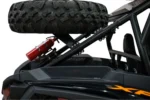 Tusk carrier holding a spare UTV tire above the bed of a Polaris RZR, with a red fire extinguisher mounted below